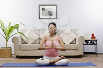 Young woman meditating in a living room