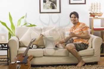 Young man holding a coffee mug in the living room