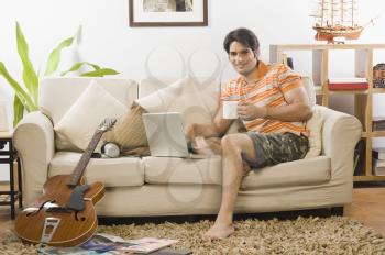 Young man holding a coffee mug in the living room