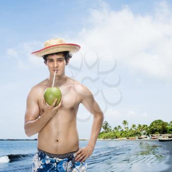 Man drinking coconut milk on the beach