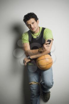 Man holding a basketball with a mobile phone