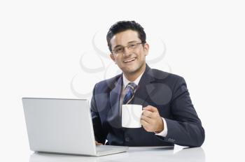 Businessman drinking coffee while working on a laptop