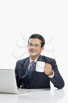 Businessman drinking coffee while working on a laptop