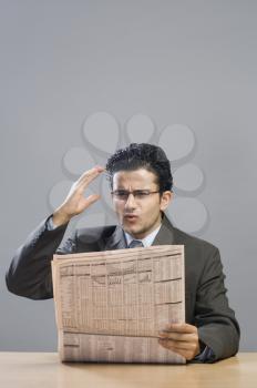 Businessman reading a financial newspaper and looking disappointed