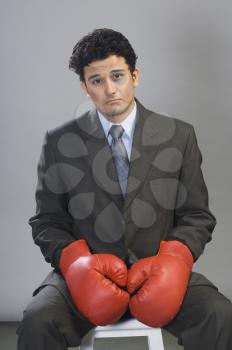 Bruised businessman wearing boxing gloves