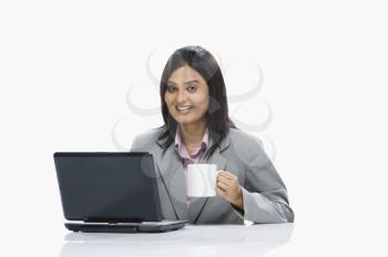 Businesswoman  drinking coffee while working on a laptop