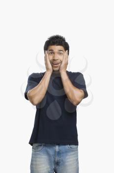 Man looking surprised with his head in his hands