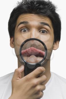 Man sticking his tongue out in front of a magnifying glass