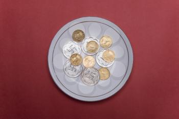Close-up of gold and silver coins in a plate