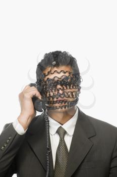 Businessman on the phone with his face covered by phone cord