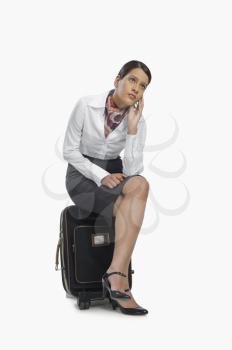 Air hostess sitting on her luggage and thinking