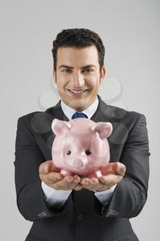 Portrait of a businessman holding a piggy bank