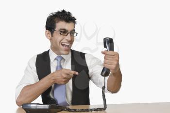 Businessman pointing at a telephone receiver and smiling