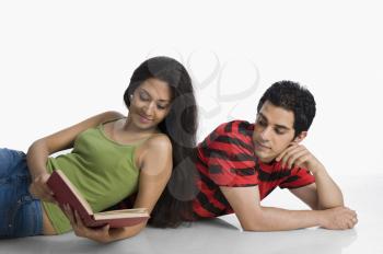 Woman leaning on a man's back and reading a book