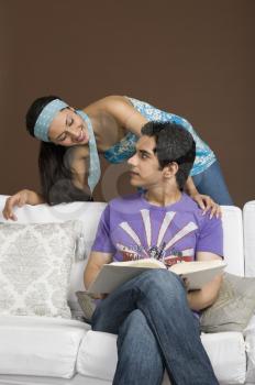 Man holding a book and looking at his girlfriend