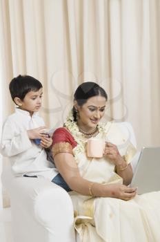 Woman using a laptop with her son and having coffee