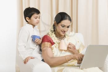Woman using a laptop with her son and having coffee