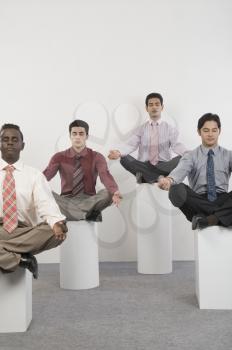 Four businessmen practicing yoga