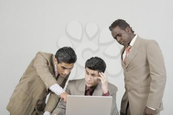 Three businessmen working on a laptop