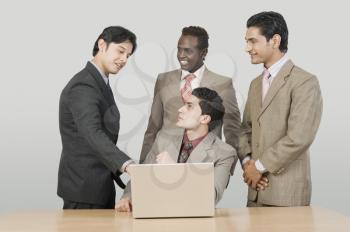 Four businessmen talking in front of a laptop