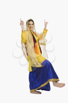 Woman in traditional yellow Punjabi dress doing bhangra
