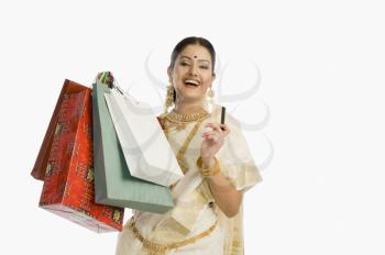 Woman in traditional South Indian sari holding shopping bags with a credit card and smiling