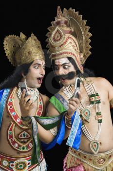 Two stage artists dressed-up as Rama and Ravana and reading text message