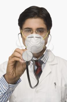 Doctor wearing a flu mask and pretending to listen heartbeat with a stethoscope