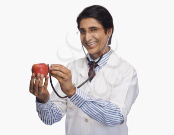 Portrait of a doctor listening to an apple with a stethoscope