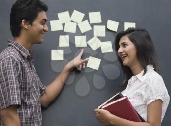 College students smiling in front of a bulletin board