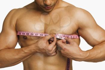 Close-up of a man measuring his chest with a tape measure