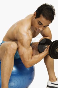 Man exercising with dumbbell on a fitness ball