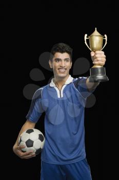 Soccer player holding a trophy with a soccer ball