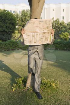 Businessman reading a newspaper in a park