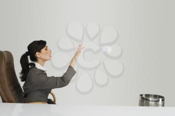 Businesswoman throwing crumpled paper into a wastepaper basket