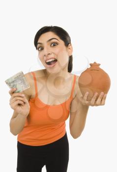 Woman holding Indian currency notes with a piggy bank