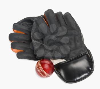 Close-up of a cricket ball with a pair of wicket keeping gloves