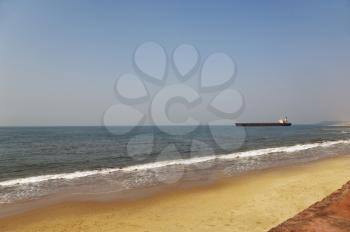 Beach with a container ship in the background, Goa, India