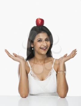 Woman balancing an apple on her head and smiling