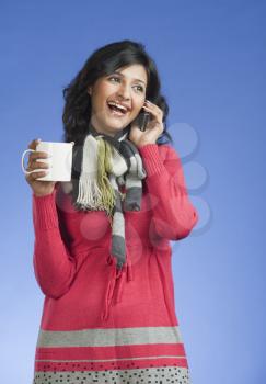 Woman holding a cup of coffee and talking on a mobile phone