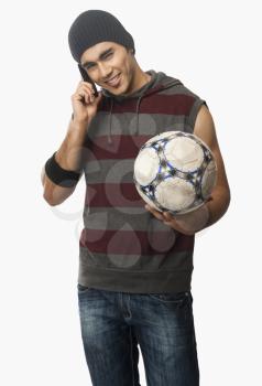 Man talking on a mobile phone and holding a soccer ball