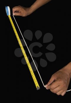 Close-up of a man measuring string with a tape measure