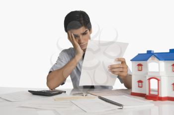 Real estate agent reading a document near a model home