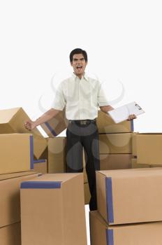 Store incharge standing among cardboard boxes and shouting