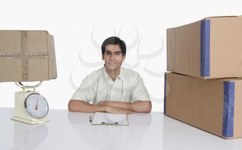 Store incharge at desk with a weight scale and cardboard boxes