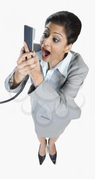 Businesswoman shouting into a telephone receiver