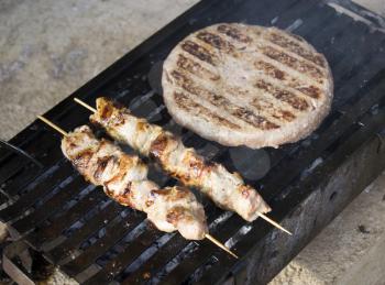 Royalty Free Photo Big Serbian Pljeskavica and Two Sticks of Meat on the Grill