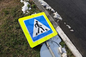 A downed road sign lies on the ground near the road