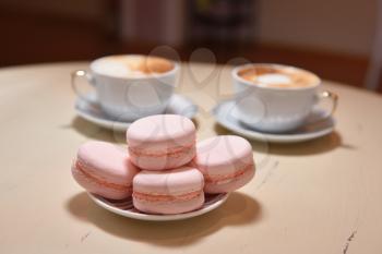 Macaroons and two cups of coffee on a vintage table.