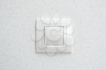 Wall mounted white light switch on white wall